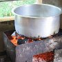 The pot with the water for the rice is boiling on the hot charcoal.